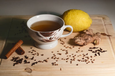 High angle view of herbal tea by spices and lemon on cutting board