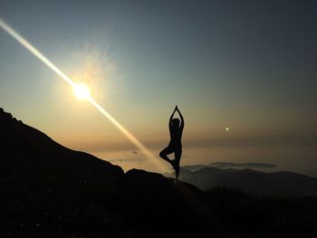 Silhouette person standing on mountain against sky during sunset