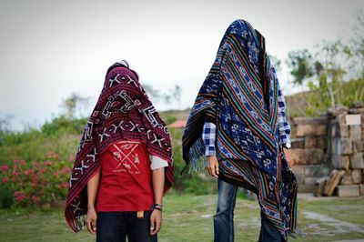 Rear view of women standing on field against sky
