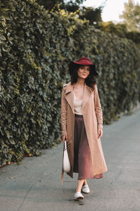 Woman wearing hat standing on footpath