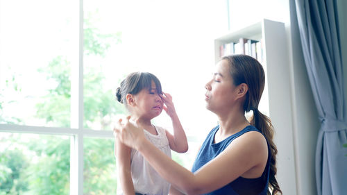 Side view of young woman against window