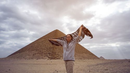 Low angle view of man standing on sand against sky