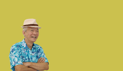 Portrait of smiling man standing against yellow background