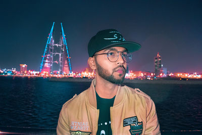 Portrait of man in illuminated city against sky at night