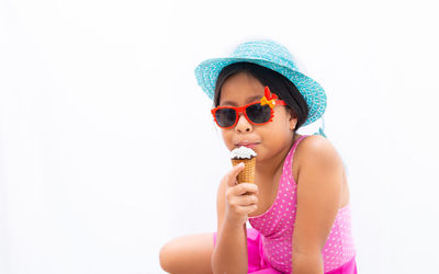 Low angle view of boy wearing sunglasses against white background