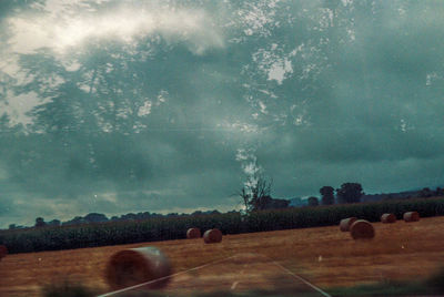 Hay bales on field against sky