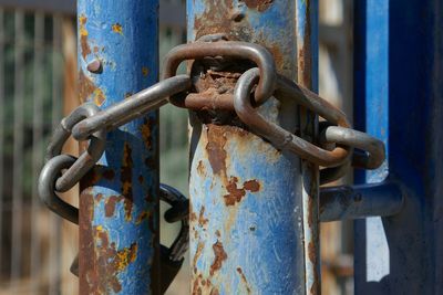 Close-up of rusty chain tied up to poles