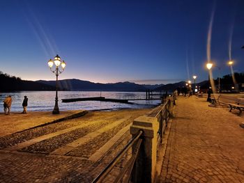 Street lights on beach against clear sky at dusk