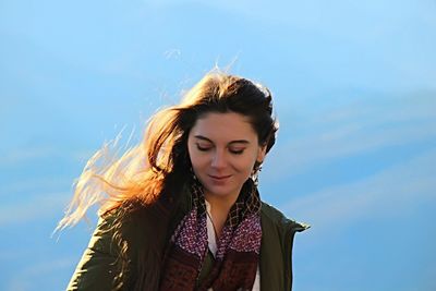 Low angle view of beautiful woman with tousled hair against sky