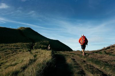 Man walking on mountain road against sky