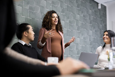 Pregnant businesswoman sharing business ideas with male and female colleagues during meeting