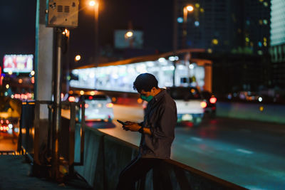 Side view of man using mobile phone at night