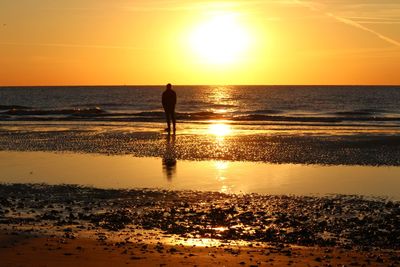 Silhouette people on beach against sky during sunset