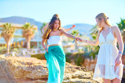 Friends holding hands while walking on rocks at resort