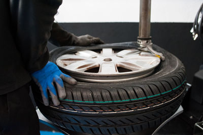 Midsection of mechanic holding tire at garage