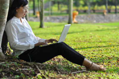 Rear view of woman using mobile phone in field