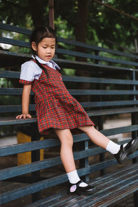 Full length of girl in school uniform sitting on bench