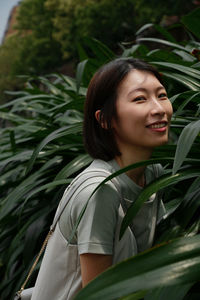 Portrait of young woman looking away against plants