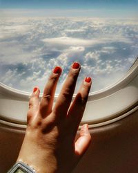 Close-up of human hand against sky