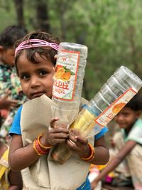 Portrait of cute girl holding plastic bottles outdoors