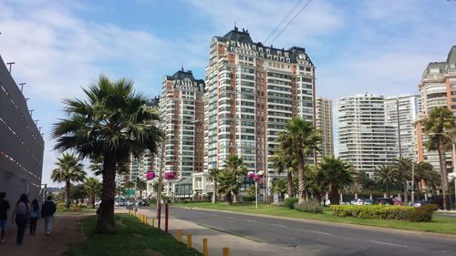 Road by buildings in city against sky