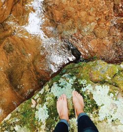 Low section of man standing on rock by water