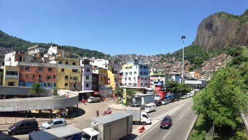 Vehicles on street amidst buildings in city against clear sky