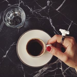 Cropped image of woman hand holding coffee cup on table