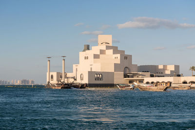 Buildings by sea against sky