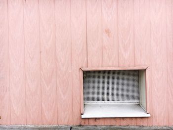 Window amidst peach wooden wall