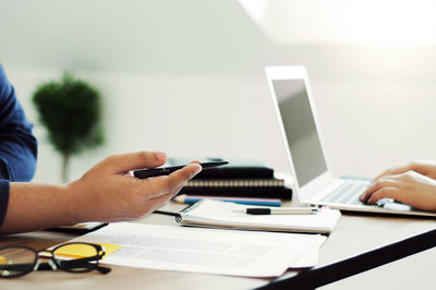 Cropped image of man using mobile phone on table