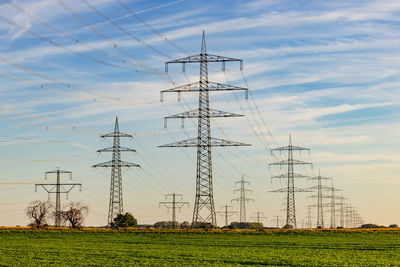 Man-made power poles and lines clash with nature at german sunset