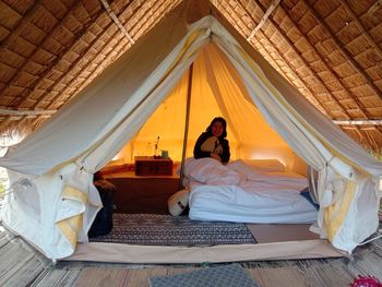 Woman sitting on bed in tent.