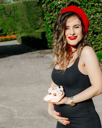 Portrait of pregnant woman holding baby booties at park