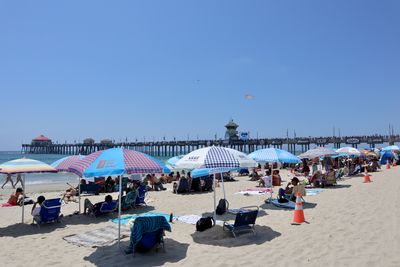 People on beach against clear blue sky