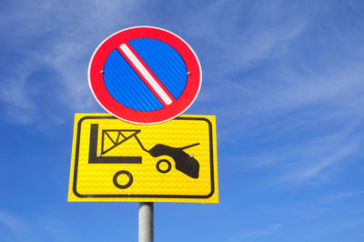 Low angle view of road sign against blue sky