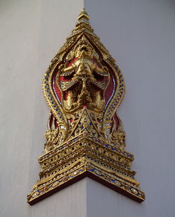 Low angle view of gold demon sculpture on wall