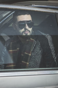 Portrait of young man seen through car window