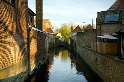 Canal amidst houses and buildings against sky