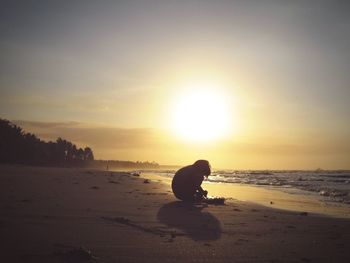 Silhouette person on beach against sky during sunset