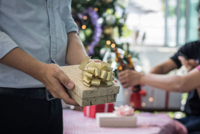 Midsection of man with gift box standing at home during christmas