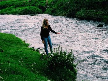 Full length of woman standing on grass by pond