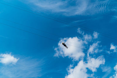 Low angle view of birds flying against blue sky