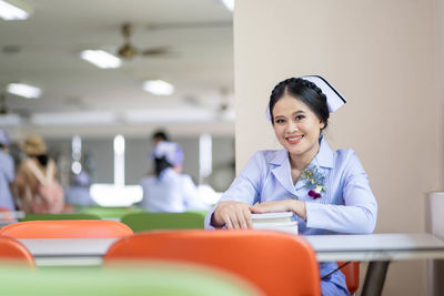 Portrait of smiling nurse sitting at table in library