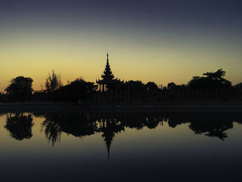 Reflection of silhouette trees in lake at sunset