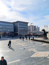 People walking in city against sky