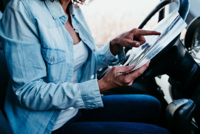 Midsection of woman analyzing map in camper trailer