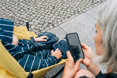 Mom uses a messenger on her mobile phone near the stroller with her sleeping son