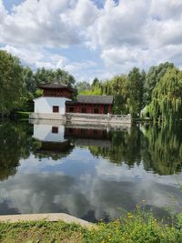 Built structure by lake and trees against sky