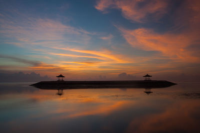 Silhouette man in sea against sky during sunset